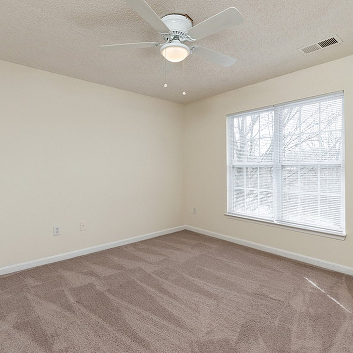 Bright and airy bedroom featuring plush carpeting, a ceiling fan, and large windows inviting natural light.
