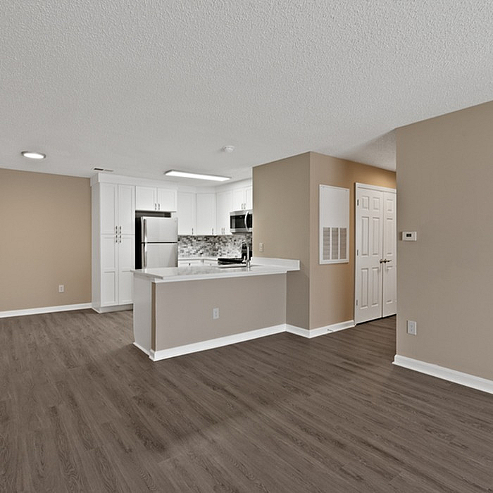 Modern open-concept apartment with sleek hardwood floors, a stylish kitchen with stainless steel appliances, and inviting neutral tones.