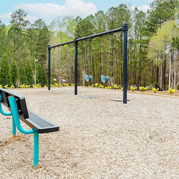 Charming outdoor play area with swings and vibrant greenery, perfect for family fun and relaxation.