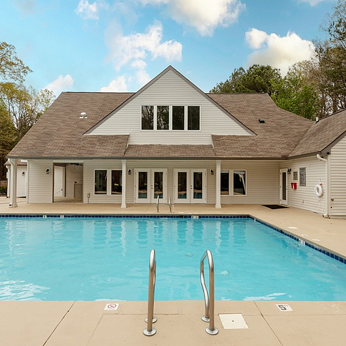 Inviting outdoor pool area next to a modern clubhouse with scenic views and ample sunlight.