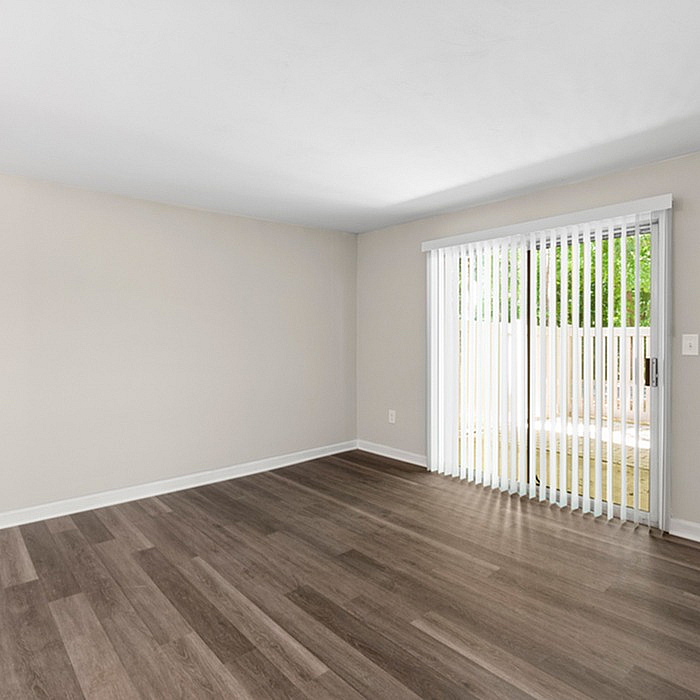 Bright, spacious living area with sleek hardwood flooring and large sliding glass doors opening to private outdoor space.