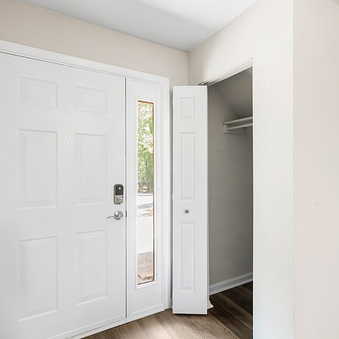 Bright entryway with sleek modern door, smart lock, and convenient closet space on elegant flooring.