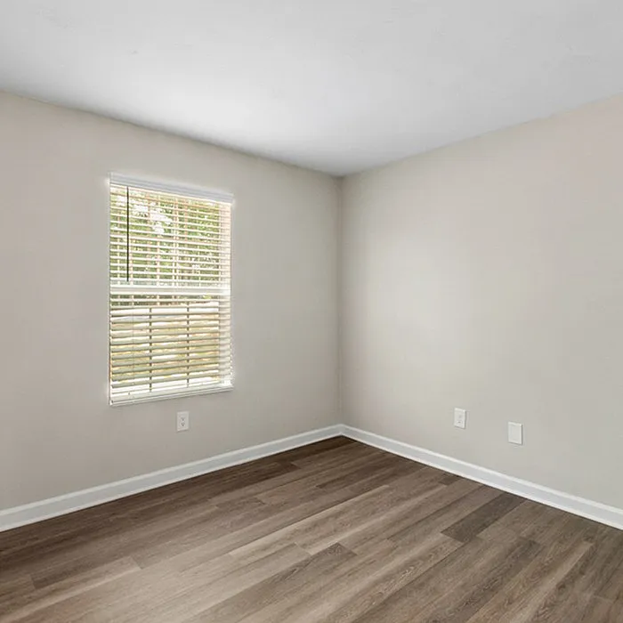 Bright and inviting empty room with large window and elegant hardwood flooring.