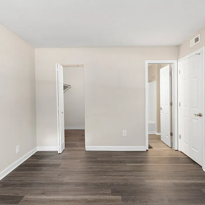 Bright and inviting bedroom with sleek wood flooring, spacious walk-in closet, and modern bathroom access.