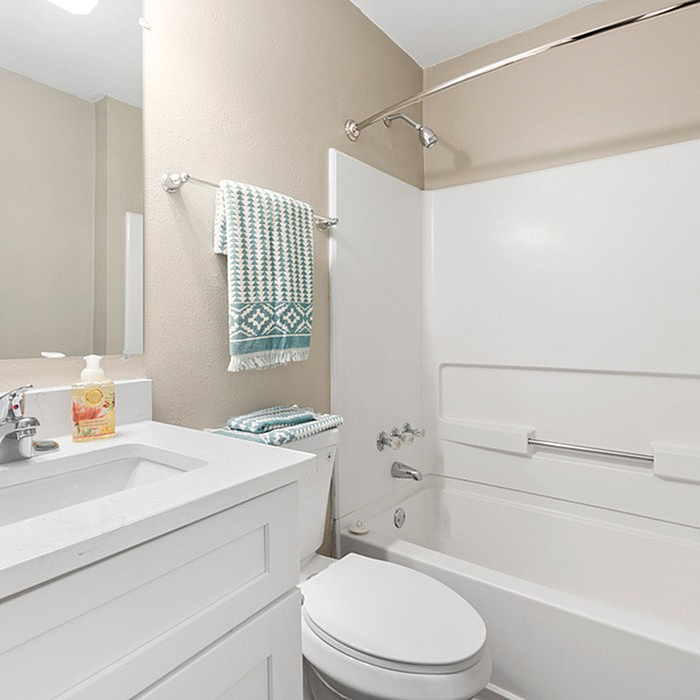 Bright and modern bathroom featuring a sleek white vanity, stylish fixtures, and a cozy bathtub with chic decor.