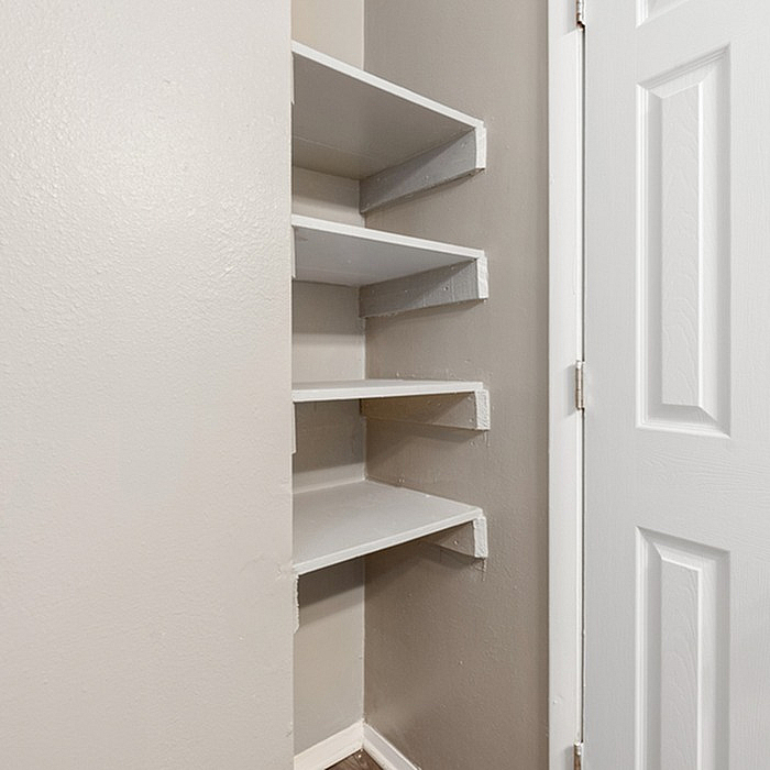 Compact corner shelving unit with sleek white shelves, perfect for maximizing storage and adding modern elegance to any room.