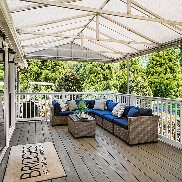 Charming covered patio with elegant wicker seating, ideal for relaxing and enjoying a lush garden view.