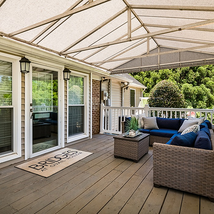 Charming outdoor deck with cozy wicker seating and lush greenery, perfect for relaxing evenings.