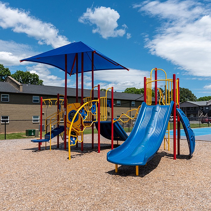 Vibrant playground with colorful slides and climbing structures set under a bright blue sky, ideal for family fun in a welcoming community.
