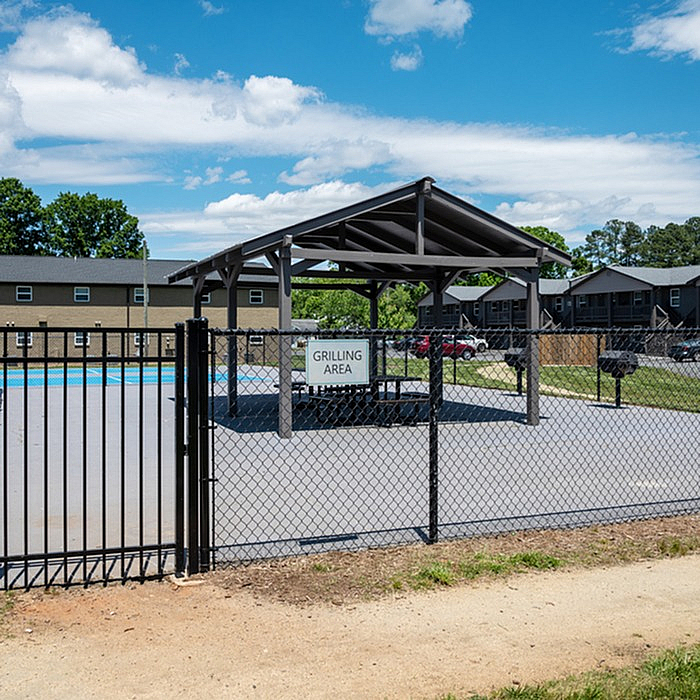 Inviting outdoor grilling area with a covered pavilion, perfect for gatherings and relaxation under a clear blue sky.