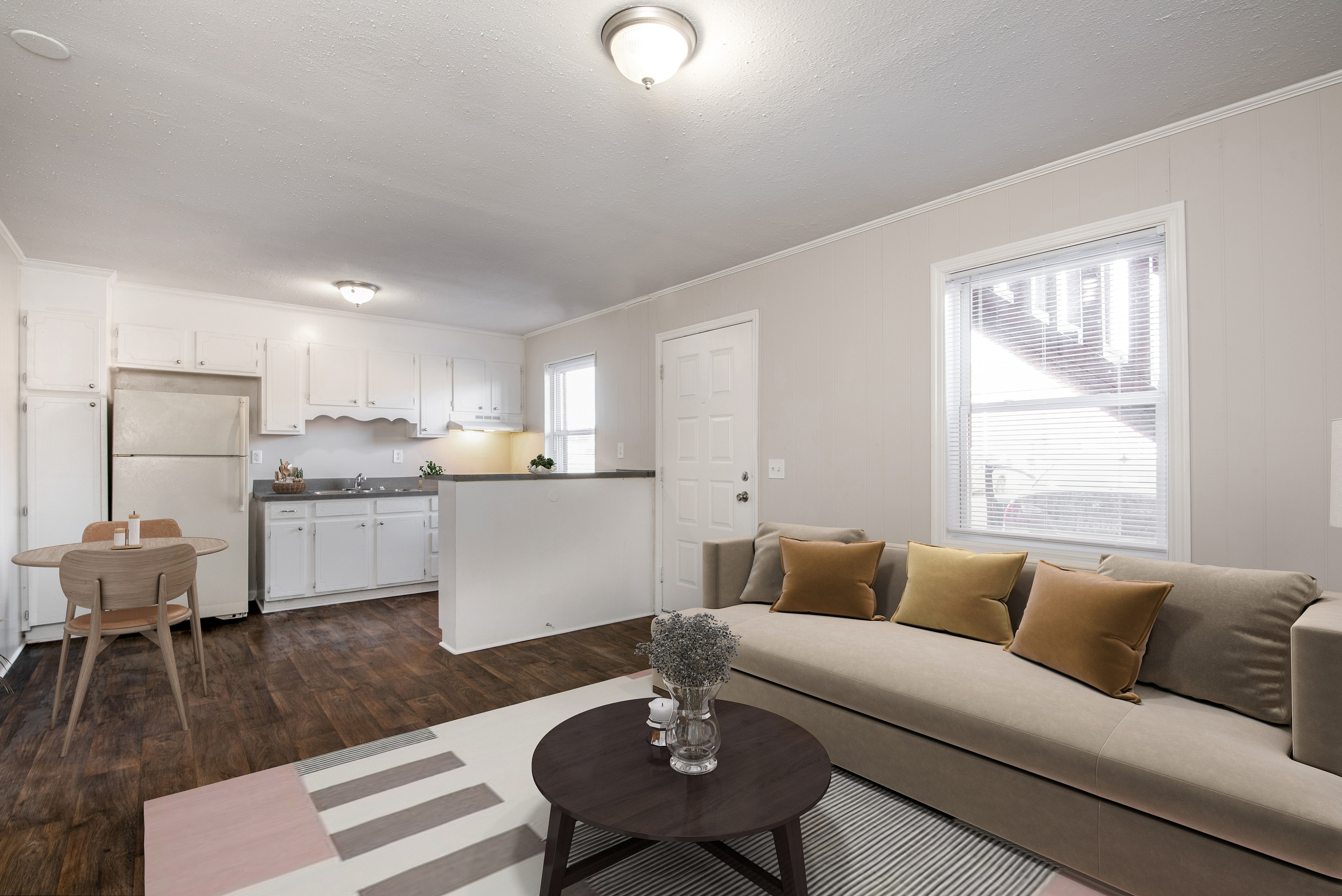 Inviting open-concept living space showcasing a modern kitchen with white cabinetry, cozy dining area, and a stylish living room with plush seating.