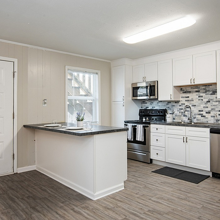 Modern kitchen featuring sleek white cabinetry, stainless steel appliances, and a stylish grey-tile backsplash.