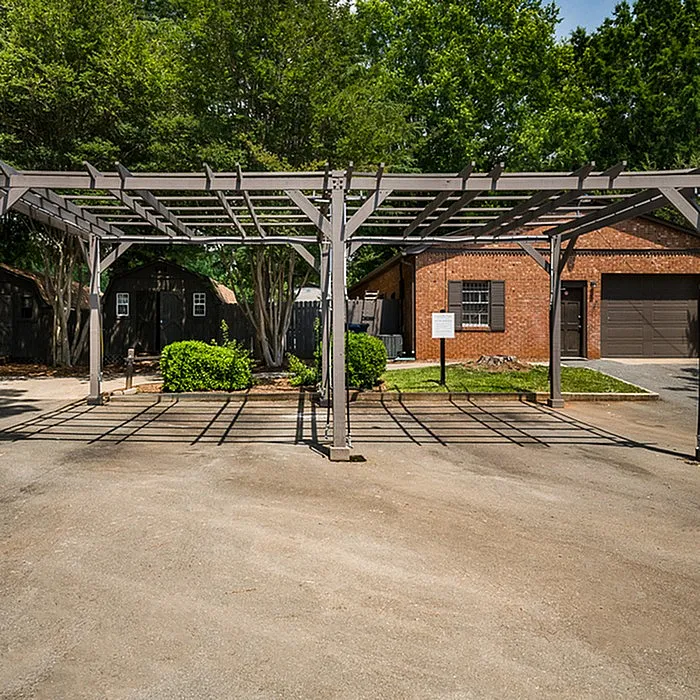 Charming outdoor view featuring a stylish pergola, lush greenery, and a rustic brick garage in a serene setting.