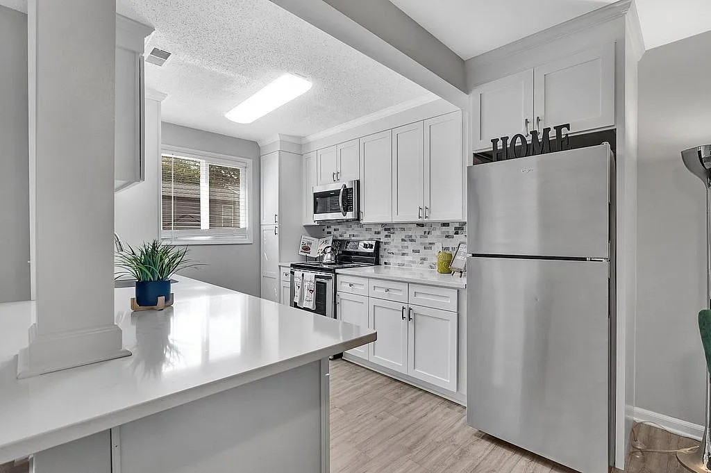Modern kitchen with sleek stainless steel appliances, elegant white cabinetry, and stylish tile backsplash, offering a bright and inviting atmosphere.