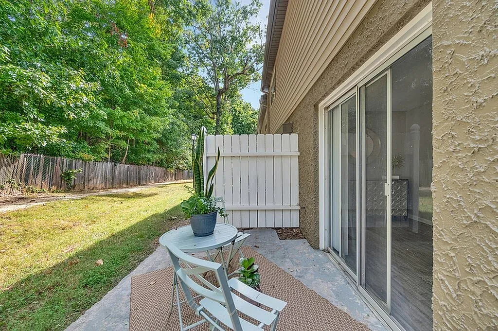 Charming outdoor patio with lush greenery, featuring a cozy seating area and elegant sliding glass doors for seamless indoor-outdoor living.