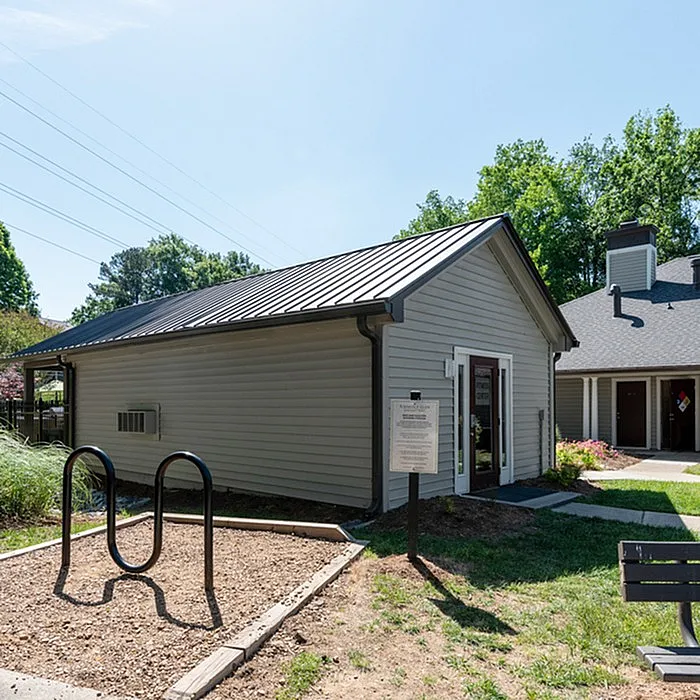 Charming outdoor view of a modern community building with sleek siding, surrounded by lush greenery and open blue skies.