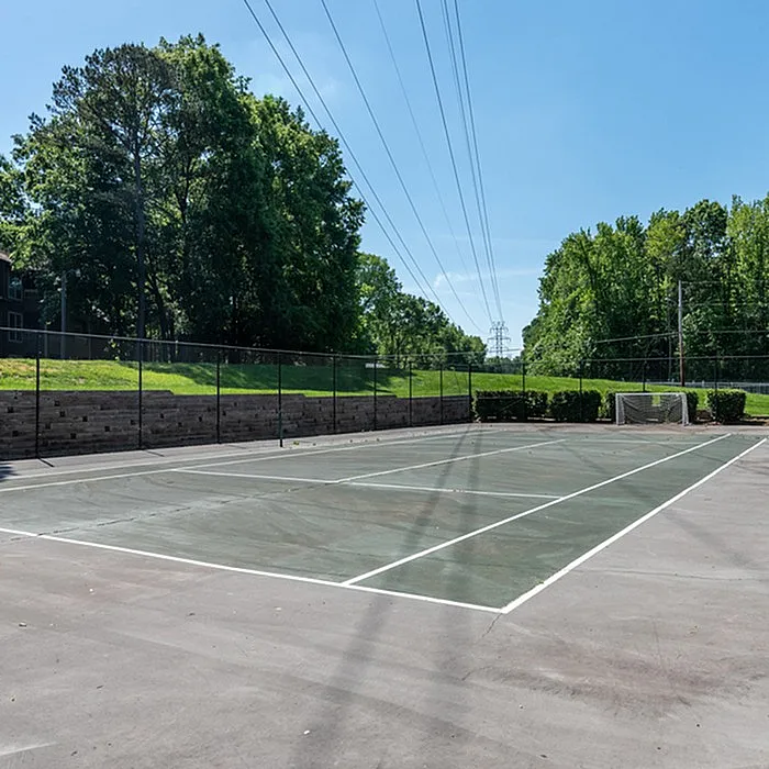 Inviting outdoor tennis court surrounded by lush greenery, perfect for sports enthusiasts seeking leisure and recreation.