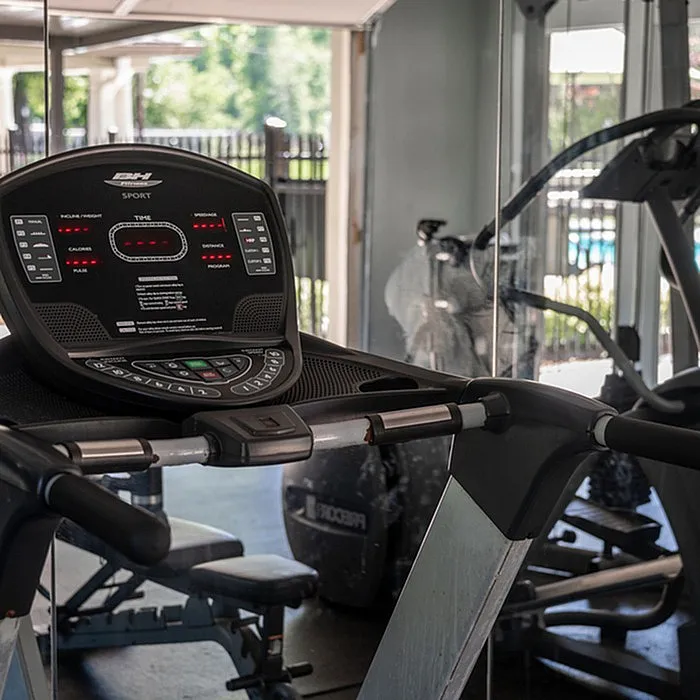 Modern fitness center featuring state-of-the-art treadmill with scenic view of outdoor pool area.