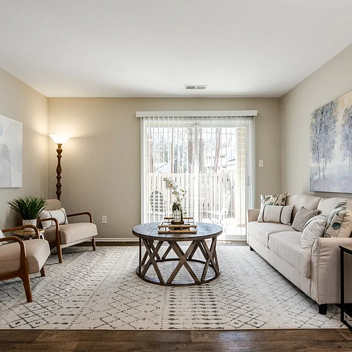 Inviting living room with elegant decor, featuring plush seating, a round wooden coffee table, and natural light streaming through glass doors.