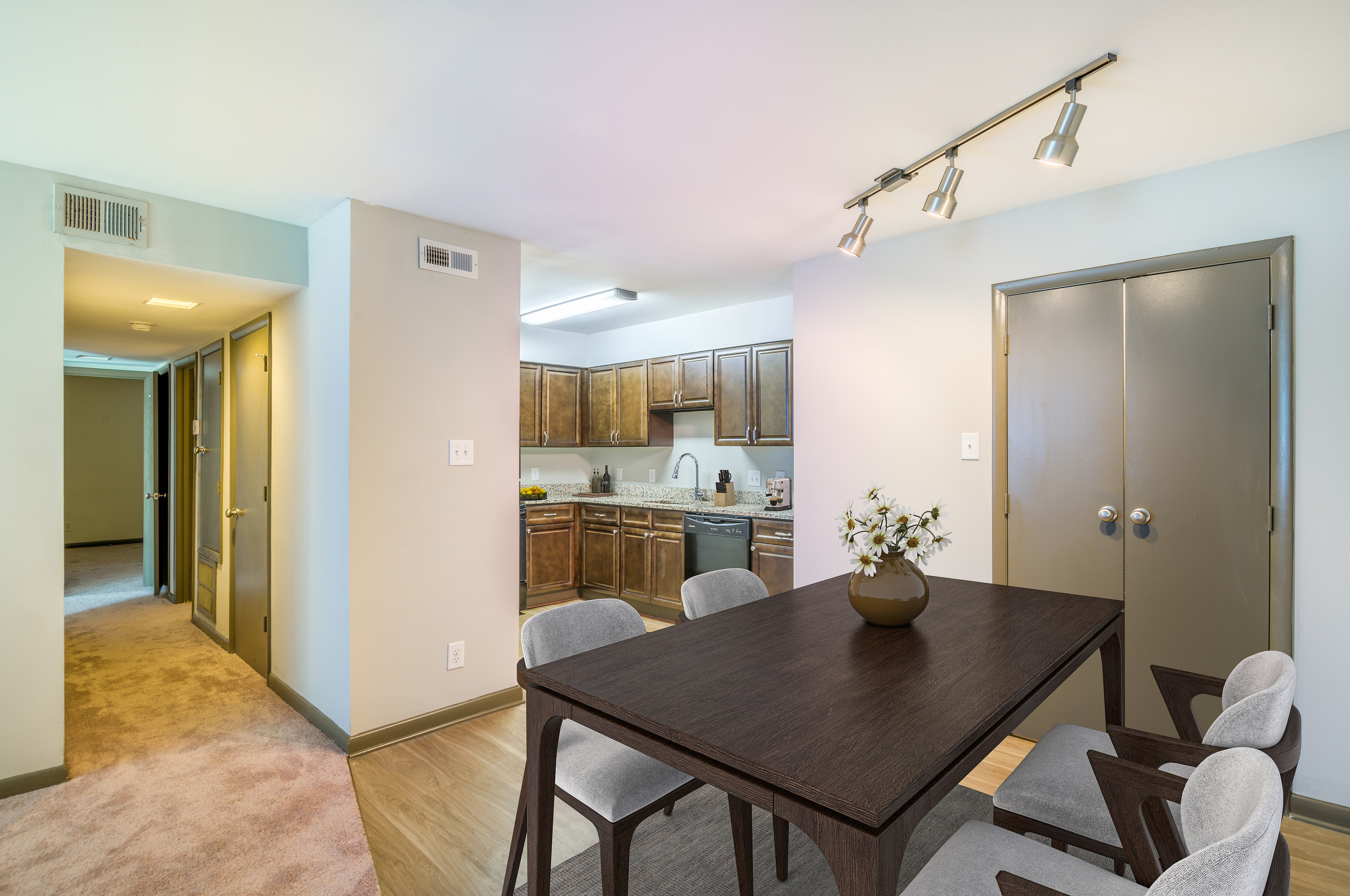 Inviting apartment interior with a cozy dining area adjacent to a modern kitchen featuring sleek wooden cabinets and stylish lighting.