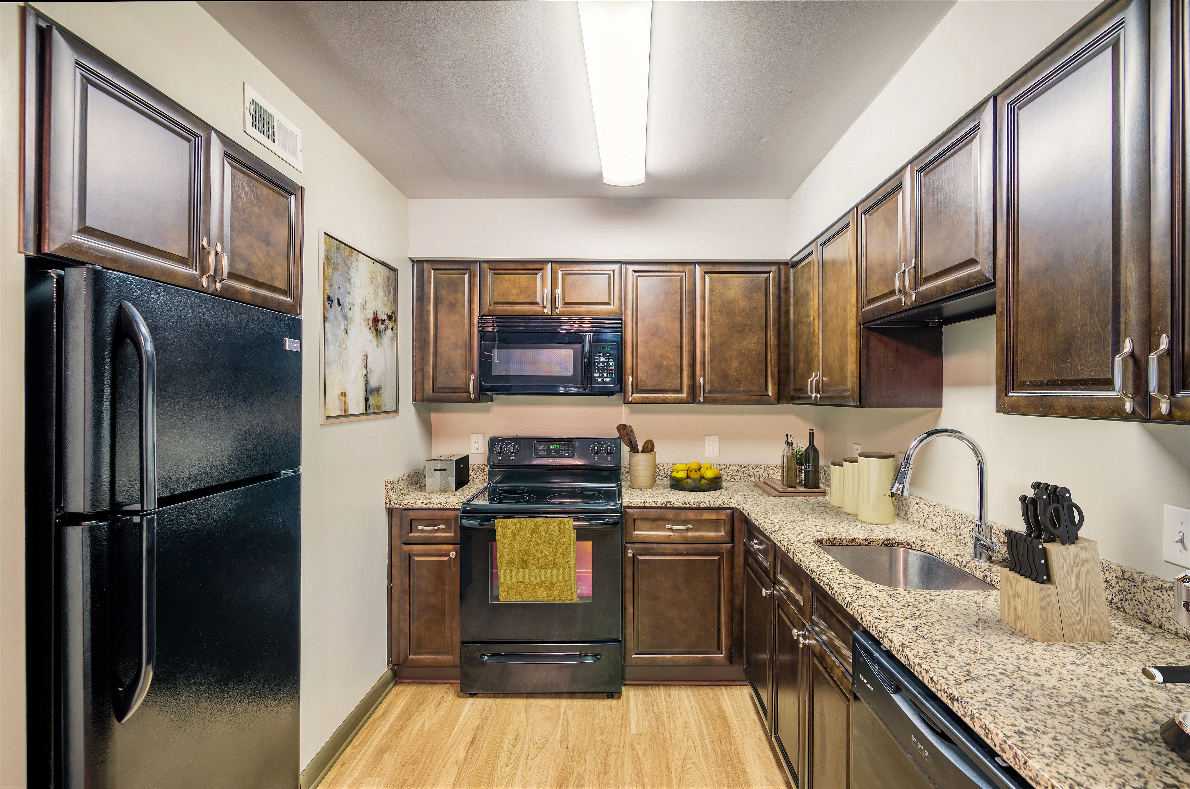 Elegant kitchen with sleek dark wood cabinets, modern appliances, and granite countertops accentuated by ambient lighting.