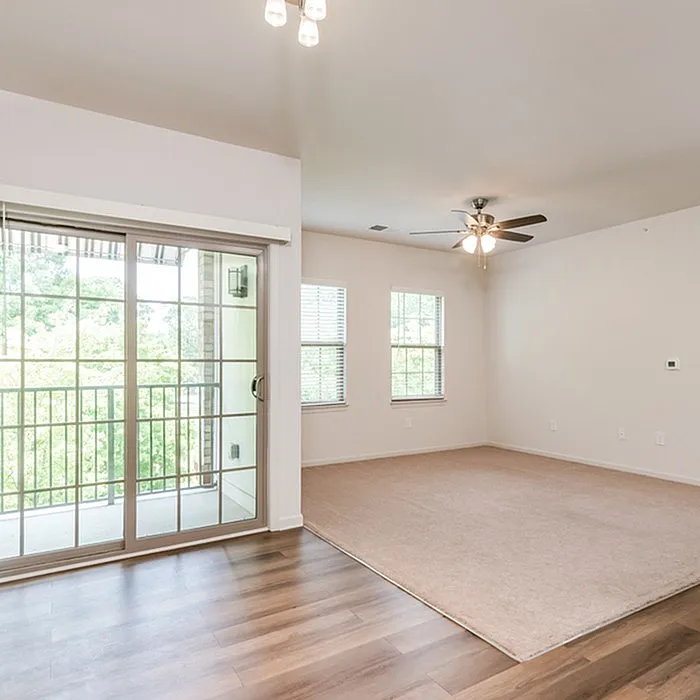 Bright and spacious living area with modern ceiling fan, large windows, and sliding glass doors leading to a balcony with scenic views.