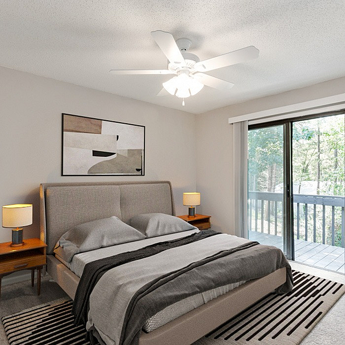 Inviting bedroom with modern decor, cozy bed, ceiling fan, and private balcony access, offering serene outdoor views.