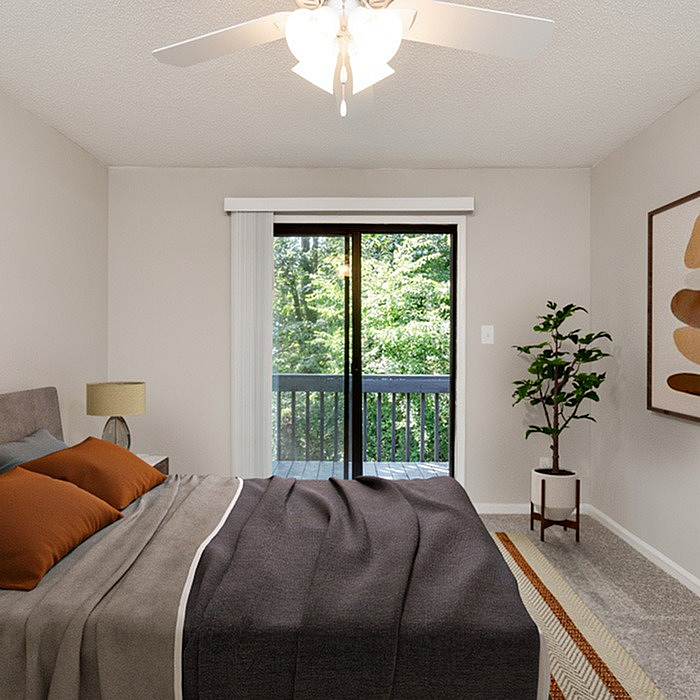 Inviting bedroom with cozy bedding, modern ceiling fan, and serene balcony view, accented by a lush indoor plant and stylish artwork.