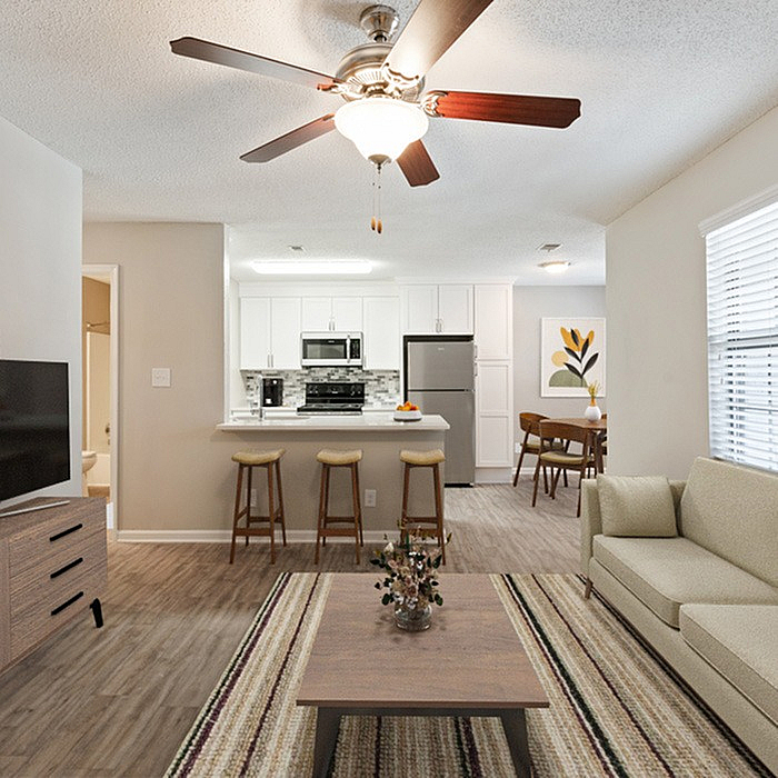 Charming open-concept living room with a cozy couch, modern kitchen with stainless steel appliances, and elegant dining area. Perfect for stylish urban living.