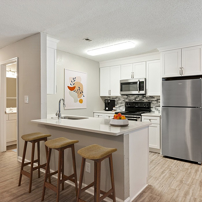 Modern kitchen with sleek white cabinets, stainless steel appliances, stylish tile backsplash, and a welcoming breakfast bar with seating.
