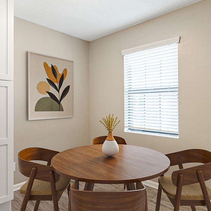 Charming dining nook with a round wooden table, elegant chairs, and contemporary artwork, bathed in natural light.
