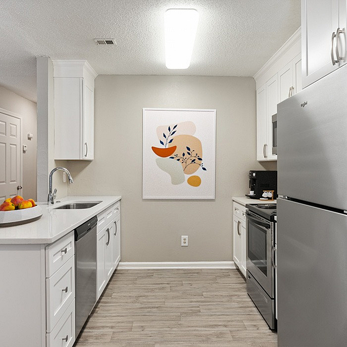Modern kitchen with sleek white cabinetry, stainless steel appliances, and elegant wall art, offering a bright and inviting cooking space.