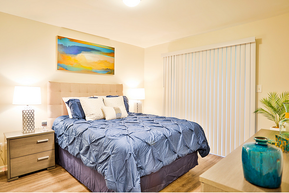 Elegant bedroom with plush blue bedding, modern nightstands, ambient lighting, and vibrant wall art creating a serene retreat.
