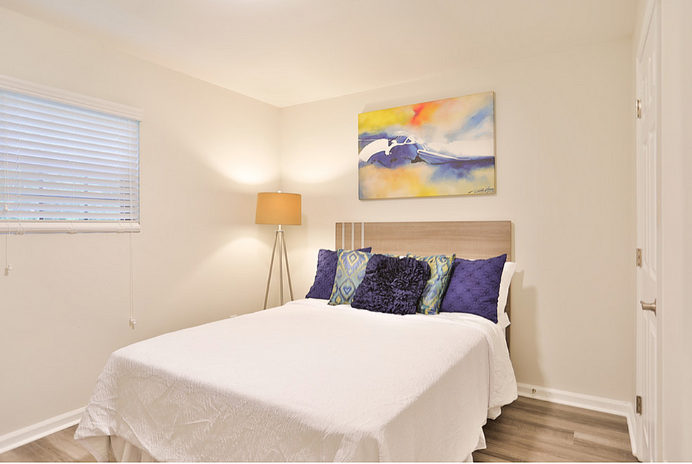 Bright and inviting bedroom with modern artwork, stylish bed set, and warm lighting fixture.