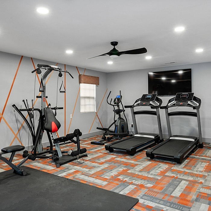 Modern gym with state-of-the-art equipment including treadmills and exercise machines, set in a stylish room with contemporary geometric design.