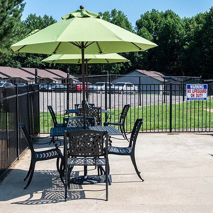Charming outdoor patio with elegant wrought iron furniture and a vibrant green umbrella, offering a perfect space for relaxation and outdoor dining.