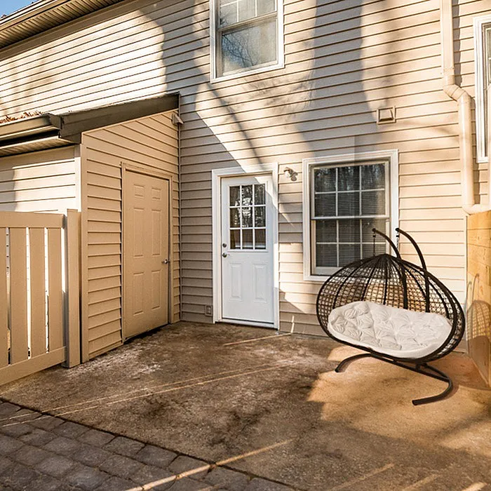Charming patio with a cozy hanging chair and sleek siding, perfect for relaxing in style.