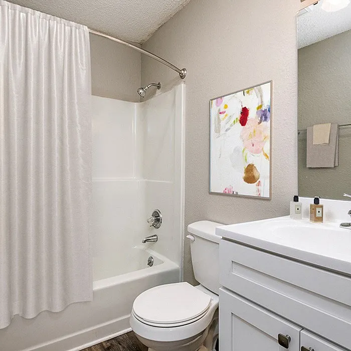 Modern bathroom with sleek white vanity, elegant shower, and artistic wall decor.