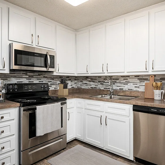 Modern kitchen with sleek stainless steel appliances, elegant white cabinetry, and stylish mosaic backsplash.