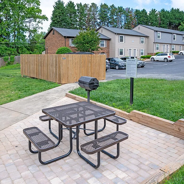 Inviting outdoor grill area with picnic table, perfect for social gatherings in a serene residential setting.