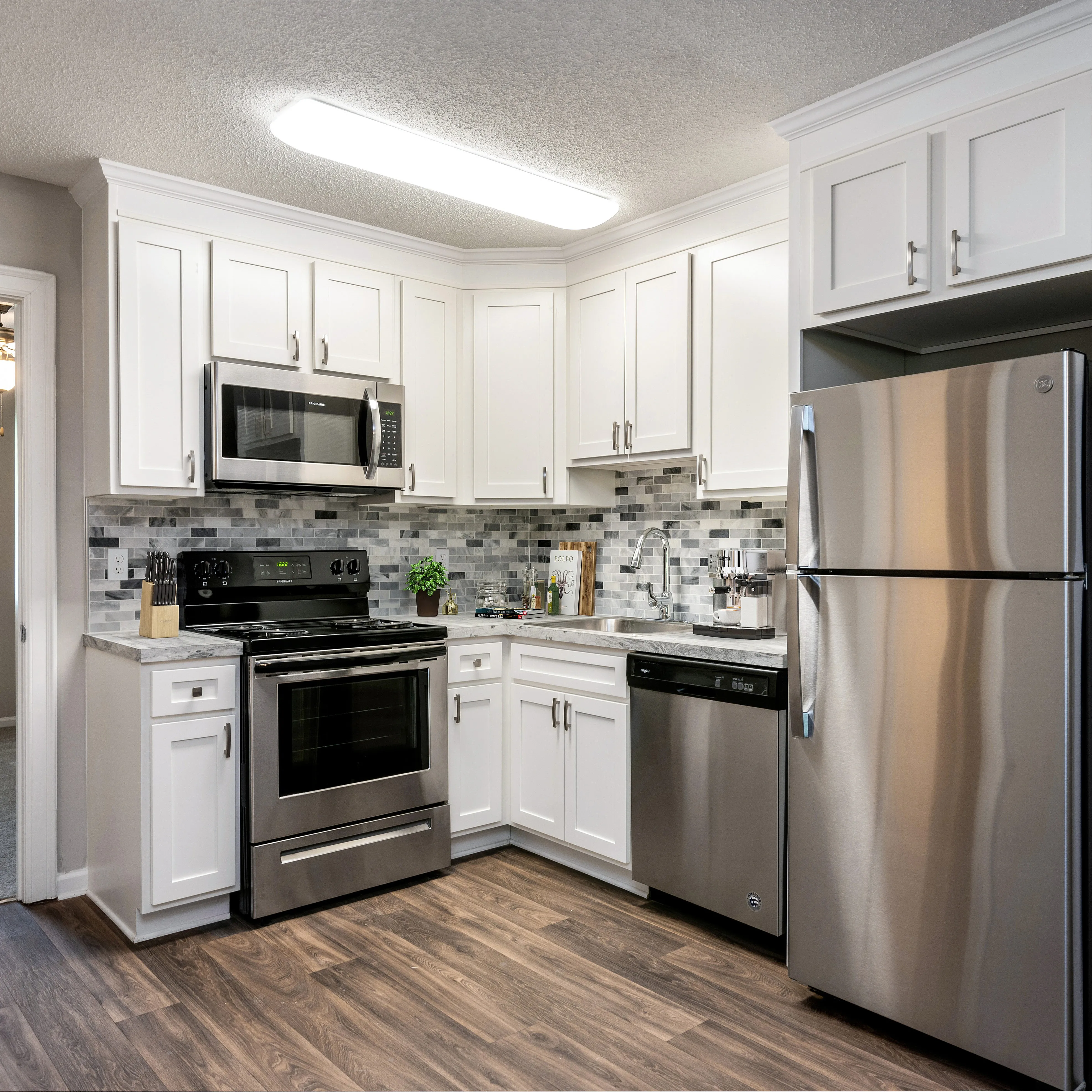 Modern kitchen with sleek stainless steel appliances, elegant white cabinetry, and stylish tile backsplash.
