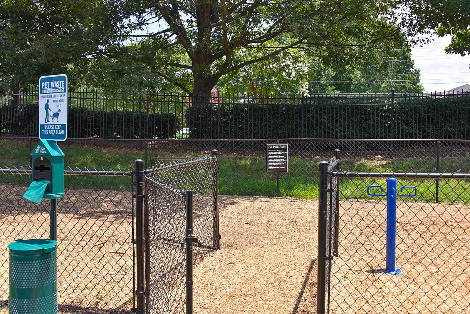 Inviting pet-friendly area featuring a clean, fenced-in dog park with waste disposal stations and beautiful surrounding greenery.