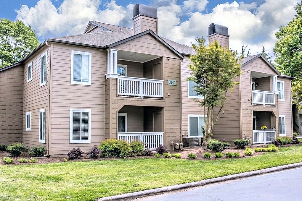 Inviting exterior of a modern apartment complex with charming balconies, lush greenery, and a welcoming atmosphere.