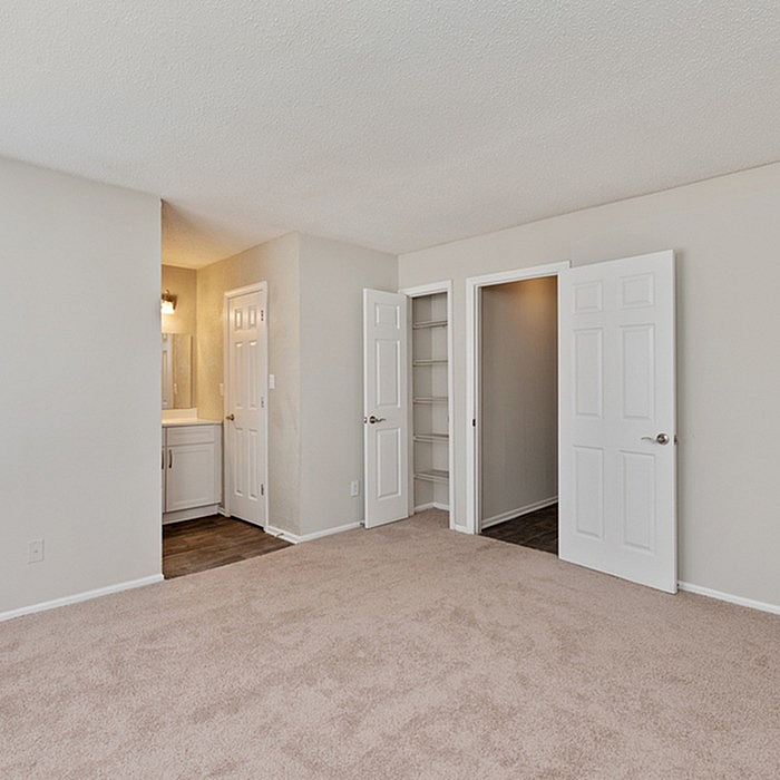 Bright, spacious bedroom with plush carpet, featuring a walk-in closet and en-suite bathroom, ideal for comfort and style.