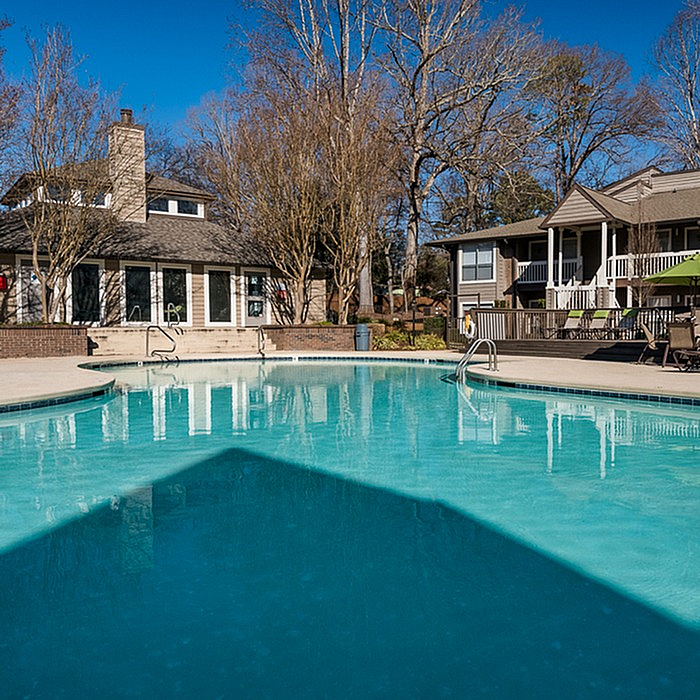 Inviting residential swimming pool surrounded by trees and charming houses, perfect for relaxation and leisure.