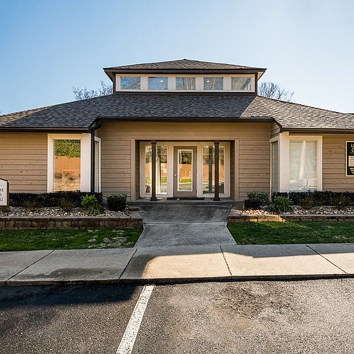 Charming entrance of a modern apartment building with a well-maintained garden and inviting pathway.