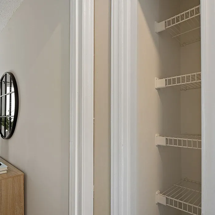 Bright and spacious hallway featuring a sleek wall mirror and open shelving for abundant storage options.