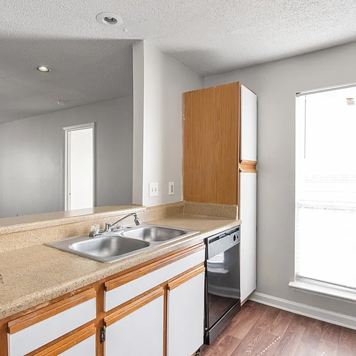 Bright kitchen showcasing modern countertops, sleek double sink, and efficient cabinetry with natural light pouring through the window.