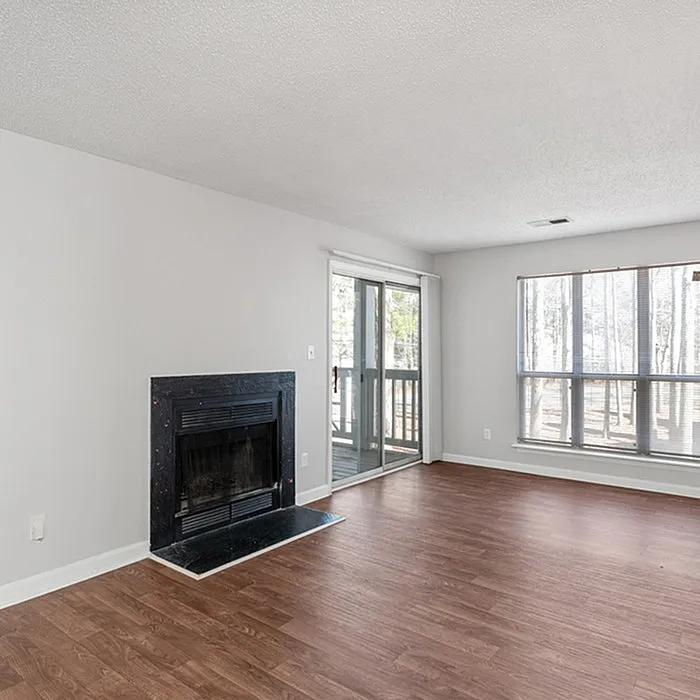 Bright and airy living room with elegant hardwood floors, a cozy fireplace, and sliding glass doors leading to a serene balcony.