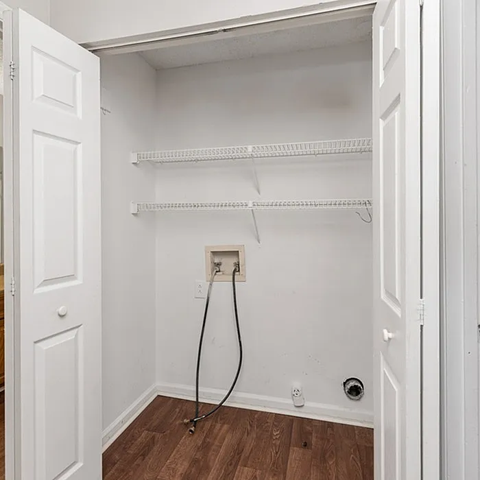 Convenient laundry closet with shelving and hookups, perfect for a modern home.